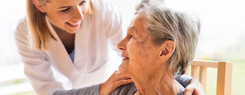 Senior woman smiling and talking to her caregiver at a senior living community