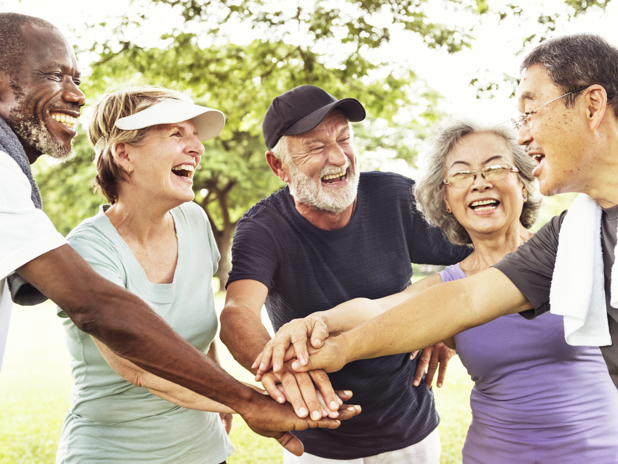 Group of elderly people laughing with hands together