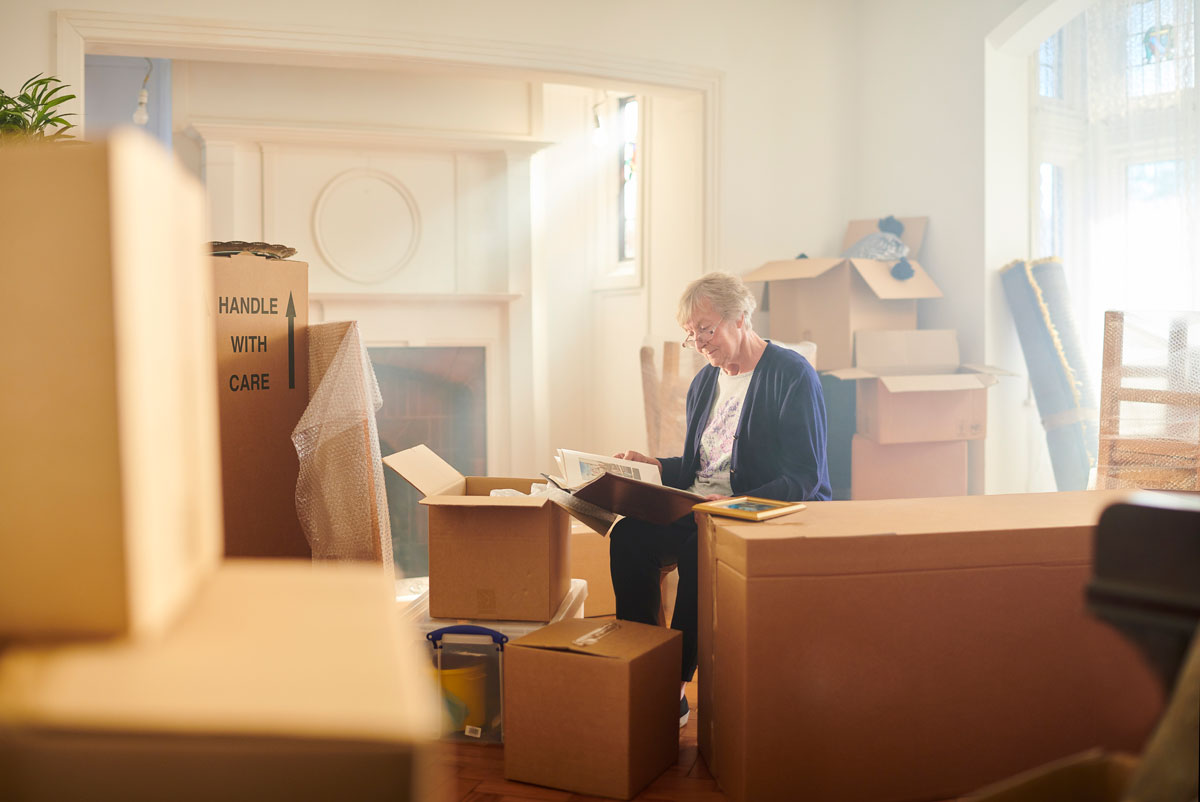 a senior man sitting around boxes in an empty apartment