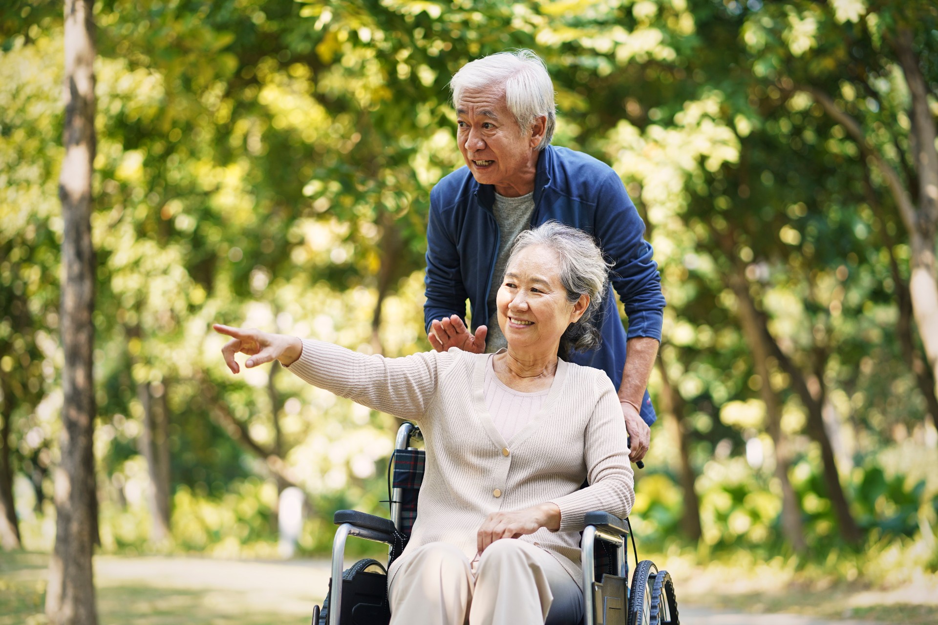 Senior man pushing his wife in a wheelchair at a park