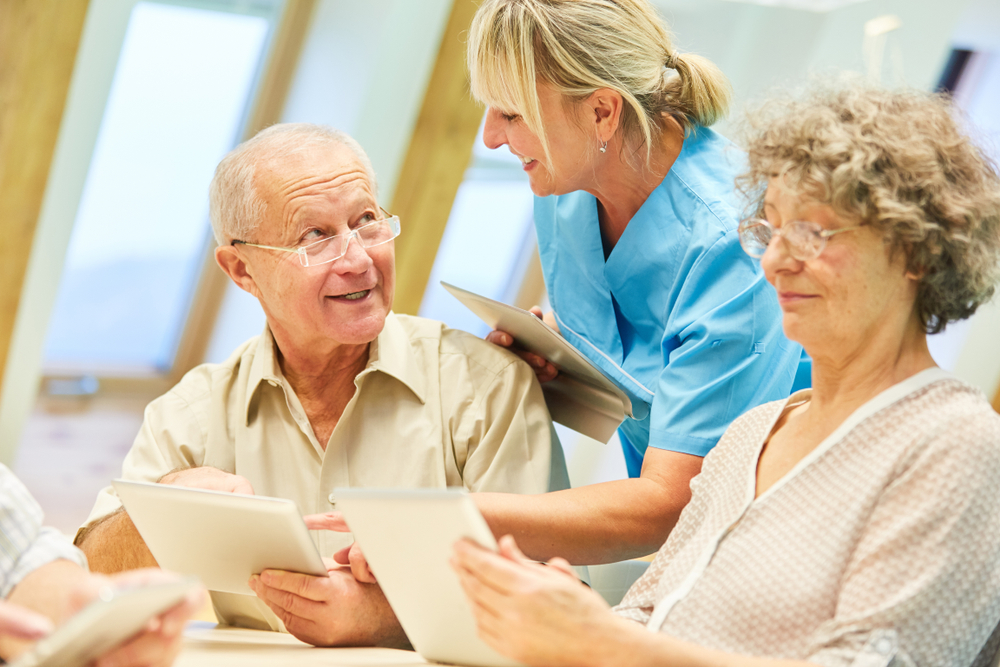 senior nurse showing residents how to use tablets