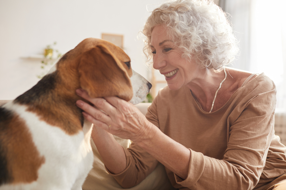 A senior woman smiles at her dog