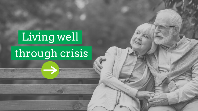 two seniors sit outside on a bench together looking at nature